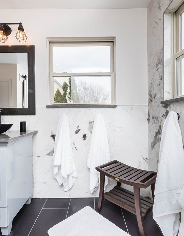 Modern Bathroom with Marble Walls and Wooden Stool