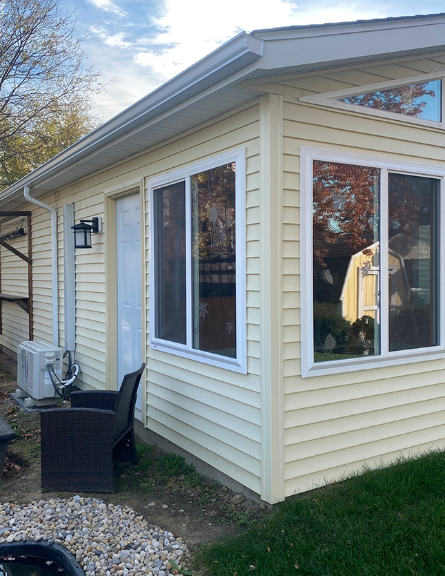 Corner View of Beige House with Large Windows and Patio Chair