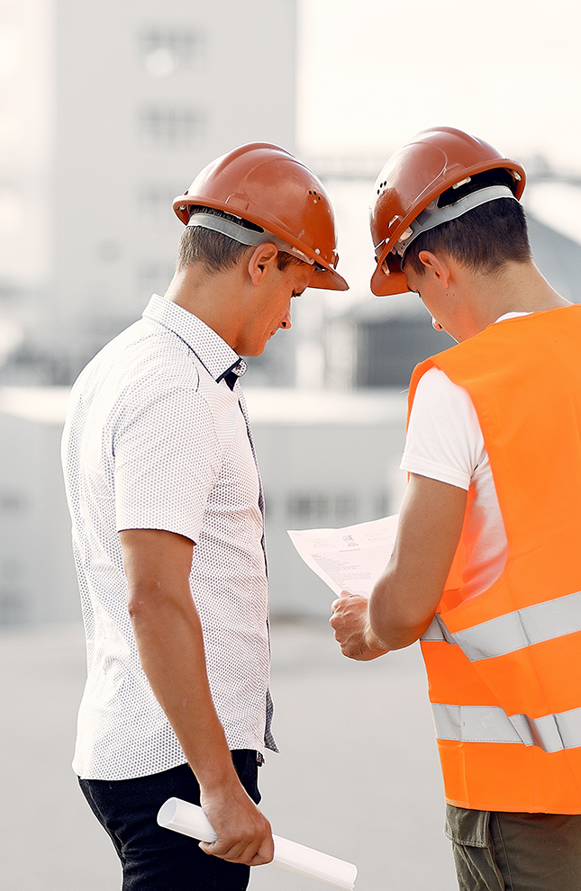 Two Construction Workers Reviewing Blueprints on a Building Site