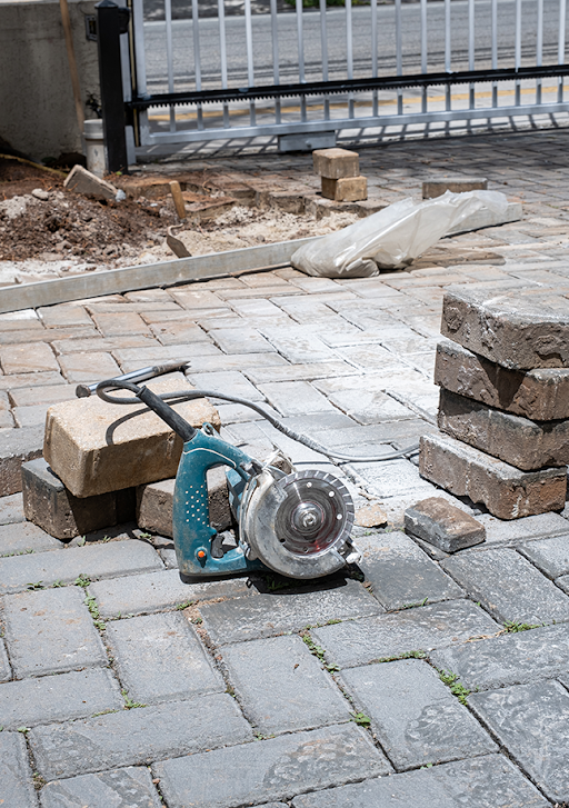 Brick Patio Under Construction with Power Tool and Stacked Bricks Nearby