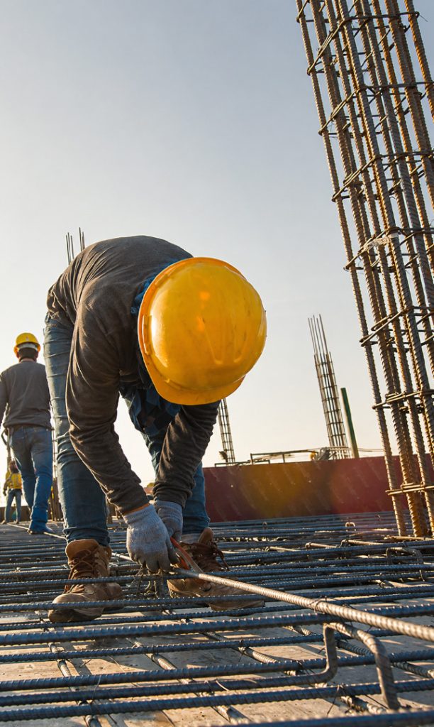 Construction Worker Securing Steel Rebar at Ground Up Construction Site